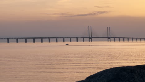 A-Shot-Of-Oresund-Bridge-With-A-Lonely-Boat-At-Golden-Hour---Malmo,-Sweden