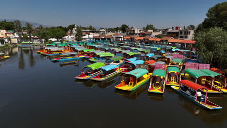 Drohne-Fliegt-über-Trajinera-Boote,-Die-Am-Xochimilco-See-Im-Sonnigen-Mexiko-Angedockt-Sind