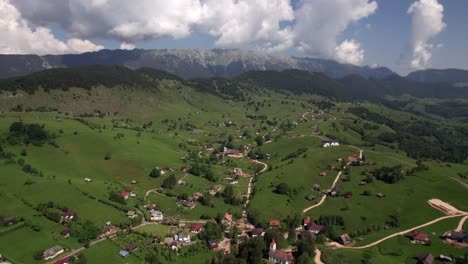 Sirnea-village-nestled-in-green-piatra-craiului-mountains-on-a-sunny-day,-aerial-view