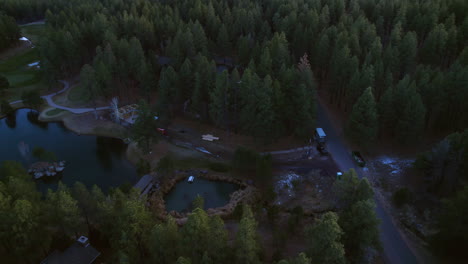 Vista-Aérea-De-Una-Pequeña-Comunidad-Americana-Aislada,-Casas-Y-Un-Lago-En-Lo-Profundo-Del-Bosque-Al-Amanecer.