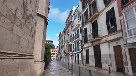 Old-city-centre-in-Palma-de-Mallorca-a-street-after-rain-with-blue-sky-and-palm-trees,-buildings