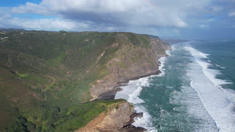 Meereswellen-Plätschern-Auf-Die-Zerklüfteten-Waitakere-Ranges-In-Piha,-Westküste-Von-Auckland,-Neuseeland