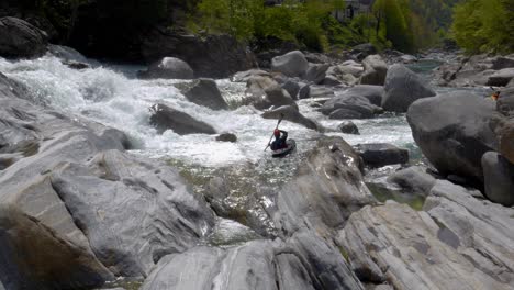 Near-to-a-waterfall,-kayaker-in-the-wild-stream-near-Lavertezzo,-Verzasca-valley-between-big-stones