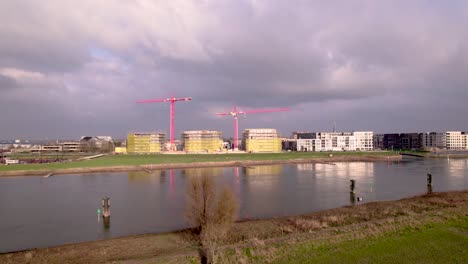 Río-Aéreo-Ijssel-Pasando-Por-El-Barrio-Holandés-De-Nueva-Construcción-Noorderhaven-Con-Grullas-Rojas-Elevándose-Sobre-El-Sitio-De-Construcción