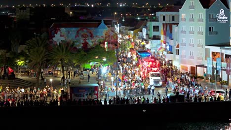 El-Desfile-De-La-Gran-Marcha-Rodea-Los-Edificios-Frente-Al-Mar-Por-La-Noche,-Descripción-Aérea