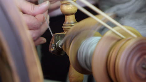 Close-up-thru-bobbin:-artisan-hands-spin-wool-on-Nordic-spinning-wheel