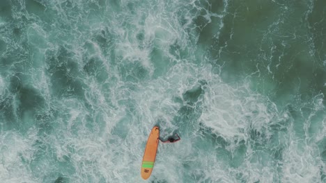 Un-Surfista-Lucha-Contra-Las-Olas-En-Una-Hermosa-Playa-De-Aguas-Verdes-Transparentes