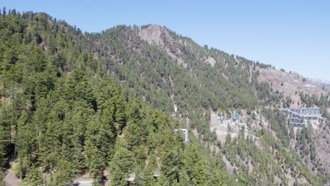 National-Park-in-Pakistan,-showcasing-dense-forests-and-scattered-buildings-on-a-rugged-mountain-terrain