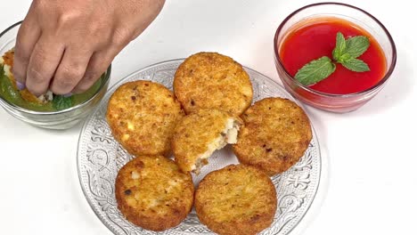 Indian-cook's-hand-putting-layers-of-Meethi-Chutney-Saunth-on-Aloo-Tikki---Street-food-from-India