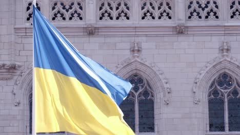 National-flag-of-Ukraine:-Ukrainian-flag-waving-in-front-of-historic-architecture