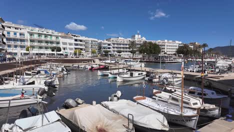 Traditional-old-port-in-Cala-Bona-with-small-fishing-boats,-small-hotels-and-restaurants-on-a-sunny-blue-day,-Majorca,-Spain