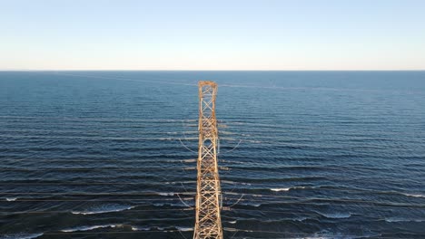 A-lone-industrial-tower-standing-in-the-waters-near-hamilton,-ontario-at-dusk,-aerial-view