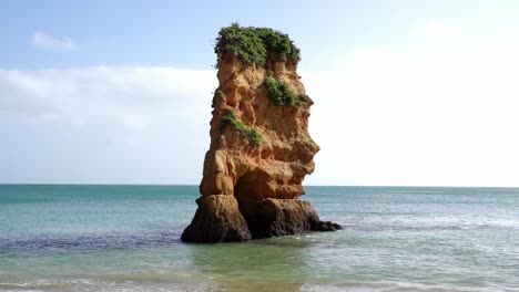 Lone-Sea-Pillar-With-A-Natural-Archway-Standing-Over-The-Turquoise-Blue-Coast-Of-Lagos,-Algarve,-Southern-Portugal