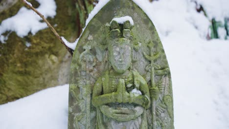 Japanese-Buddhist-Statue-in-the-Snow,-Close-Tilt-Over-Yamadera-Shrine-Idol