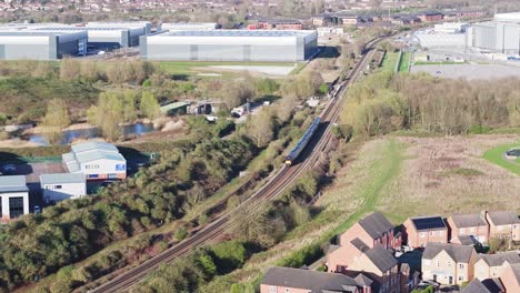 Eine-Draufsicht-Auf-Einen-Filmreifen-Personenzug,-Der-Auf-Einer-Kurvenreichen-Eisenbahnstrecke-In-Debry,-Großbritannien,-An-Den-Lagerhäusern-Entlangfährt