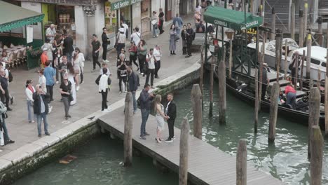 People-With-A-Romantic-Couple-Taking-Photos-On-The-Pier-Near-Rialto-Bridge-In-Venice,-Italy