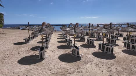 Playa-De-Arena-De-Mallorca-En-Cala-Bona-Con-Tumbonas-Y-Sombrillas-Esperando-La-Temporada-Azul-Soleado