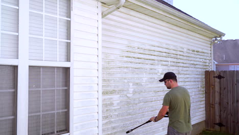 Homeowner-sets-down-pressure-washer-while-cleaning-house