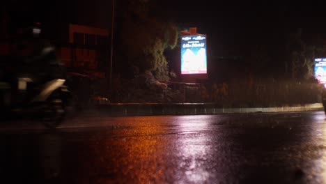 Reflexiones-Sobre-La-Carretera-Asfaltada-Mojada-En-Un-Tráfico-Lluvioso-Por-La-Noche-En-Indonesia