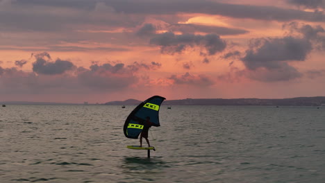 Windsurfer-Wing-Foiling-Across-A-Pink-Sunset-Sky-Over-Mui-Ne-Bay,-Phan-Thiet,-Vietnam