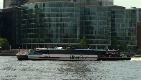 Uber-boat-sails-along-the-river-Thames,-London-passing-under-Tower-Bridge-followed-by-a-Thames-Rib-experience-boat