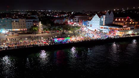 Leuchtende-Lichter-Der-Parade-Spiegeln-Sich-Nachts-Im-Karibischen-Wasser-Mit-Bunten-Gebäuden