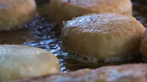 Extreme-close-up-shot-of-freshly-made-Chinese-meat-pie-cooking-and-sizzling-on-hot-oil-pan,-popular-Asian-food-cooking-in-process