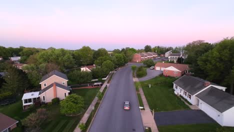 Car-on-street-in-residential-area-with-homes-and-apartment-during-sunset-time