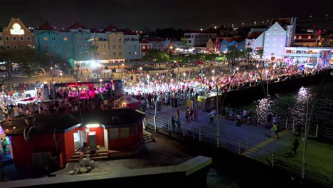 Drone-ascends-above-pontoon-bridge-as-Carnaval-performers-round-bend-at-night