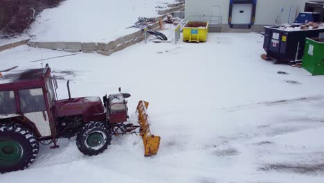 A-tractor-removes-snow-at-the-back-of-a-business