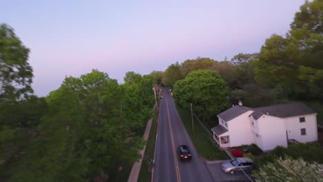 Black-car-driving-on-intersection-road-in-suburb-of-american-town