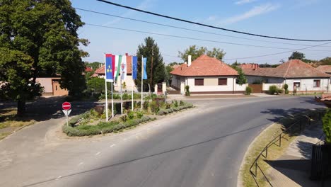 Vista-Aérea-De-Una-Calle-Encantadora-Con-Algunas-Banderas-En-Tompa,-Hungría