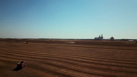 Beautiful-Midwest-Country-Landscape-Aerial-Drone-Shot-of-Grain-Truck-with-Sunset-Elevators-on-Horizon