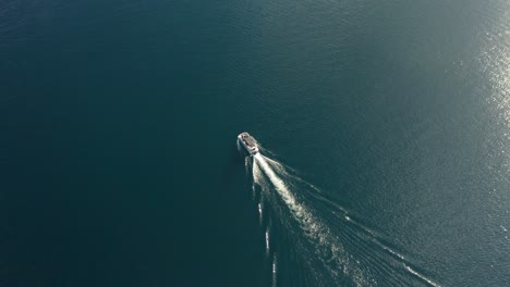 Imágenes-De-Seguimiento-De-Drones-De-Un-Barco-Navegando-En-Un-Lago-De-Gallineta-Nórdica-Rodeado-De-Agua-Azul