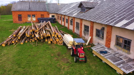 Tractor-trailer-loaded-with-planks-of-wood-and-fresh-logs-stacked,-aerial-dolly