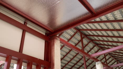 Panning-from-the-left-to-the-right-side-of-the-frame,-showing-the-metal-beams,-trusses,-rafters-and-concrete-roof-tiles-of-a-building-under-construction