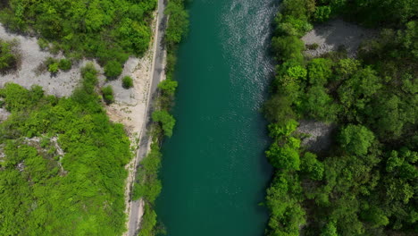 Bird's-eye-view-of-a-green-river-cutting-through-a-thick-forest,-showcasing-the-vibrant-colors-of-early-spring