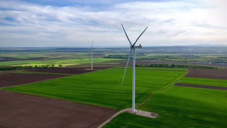 Drone-aerial-view-of-wind-turbine-in-Ruginoasa-city-of-Romania-on-a-sunny-day-with-green-grass-background