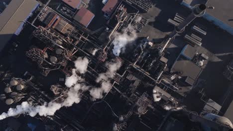 Industrial-complex-with-billowing-smokestacks-in-hamilton,-ontario-at-dusk,-shadows-stretching,-aerial-view