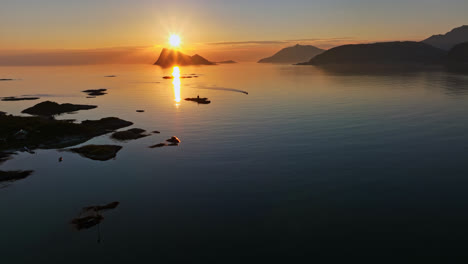 Aerial-view-of-a-boat-driving-on-the-north-coast-of-Norway,-during-midnight-sun