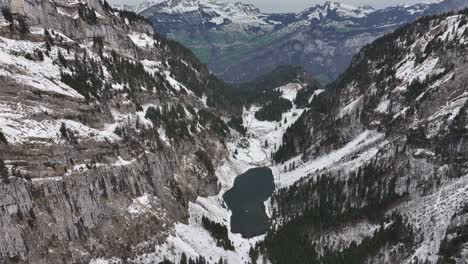 Una-Magnífica-Vista-Aérea-Captura-La-Encantadora-Belleza-De-La-Nieve,-El-Lago-Y-Las-Montañas-En-Tahlalpsee,-Filzbach,-Glarus-Nord,-Suiza
