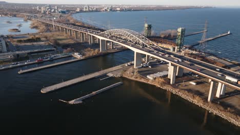 Skyway-bridge-in-hamilton,-ontario-during-golden-hour,-with-traffic-and-water,-aerial-view