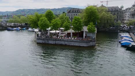 Toma-En-órbita-En-Movimiento-Hacia-La-Izquierda-De-Un-Restaurante-En-La-Ciudad-De-Zurich-Frente-Al-Río.