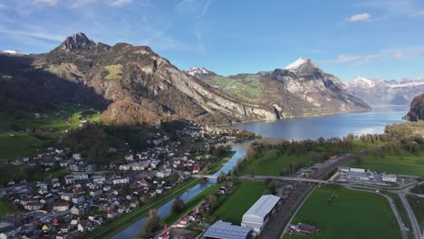 Vista-Aérea-Del-Pintoresco-Pueblo-De-Wessen,-Con-Vistas-Al-Impresionante-Lago-Walensee-Y-Los-Alpes-Suizos-Al-Fondo.