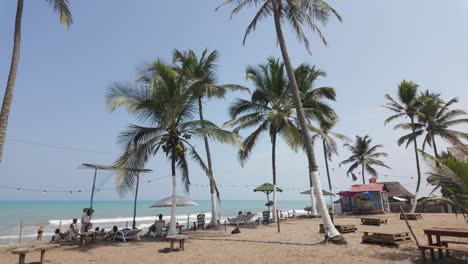 Tropical-beach-with-palm-trees-and-turquoise-colored-water,-tourists-on-vacation,-Palomino-beach,-Colombia