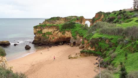 A-Beautiful-Soft-Sand-Beach-With-Lush-Green-Sea-Cliffs-And-Spectacular-Rock-Formations-In-Lagos,-Algarve,-Portugal