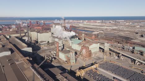 Aerial-shot-of-industrial-facilities-in-Hamilton,-Ontario-with-smokestacks-and-machinery