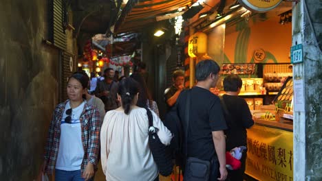 In-Der-Geschäftigen-Jiufen-Old-Street,-Einem-Bekannten-Touristenziel-In-Taiwans-Bergstadt,-Schlängeln-Sich-Große-Menschenmengen-Durch-Eine-Schmale-Gasse,-Die-Mit-Essensständen-Und-Souvenirläden-Geschmückt-Ist