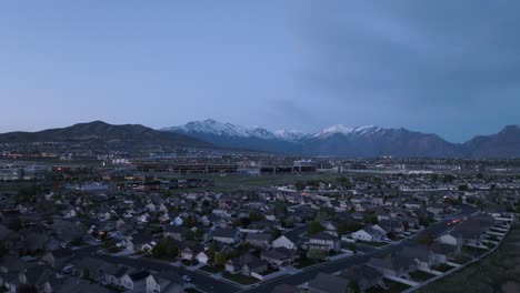 Suburbio-En-Un-Valle-Bajo-Montañas-Cubiertas-De-Nieve-Al-Atardecer---Paso-Elevado-Aéreo