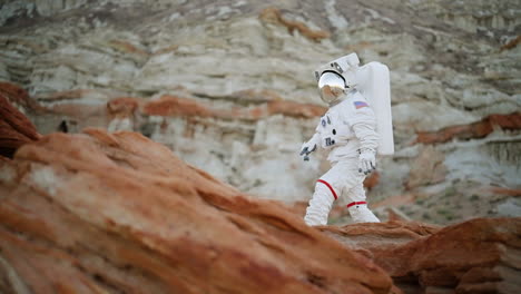 Viajero-Espacial-Estadounidense-En-Traje-Espacial,-Caminando-En-Un-Paisaje-Natural-Remoto-Y-Rocoso